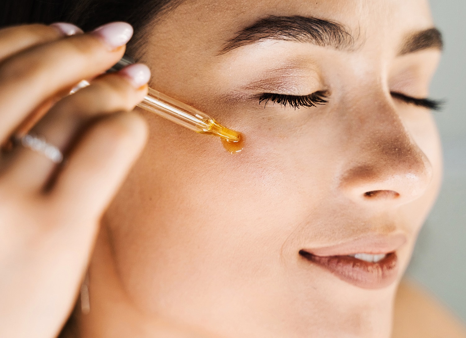 Applying facial oil with a dropper.