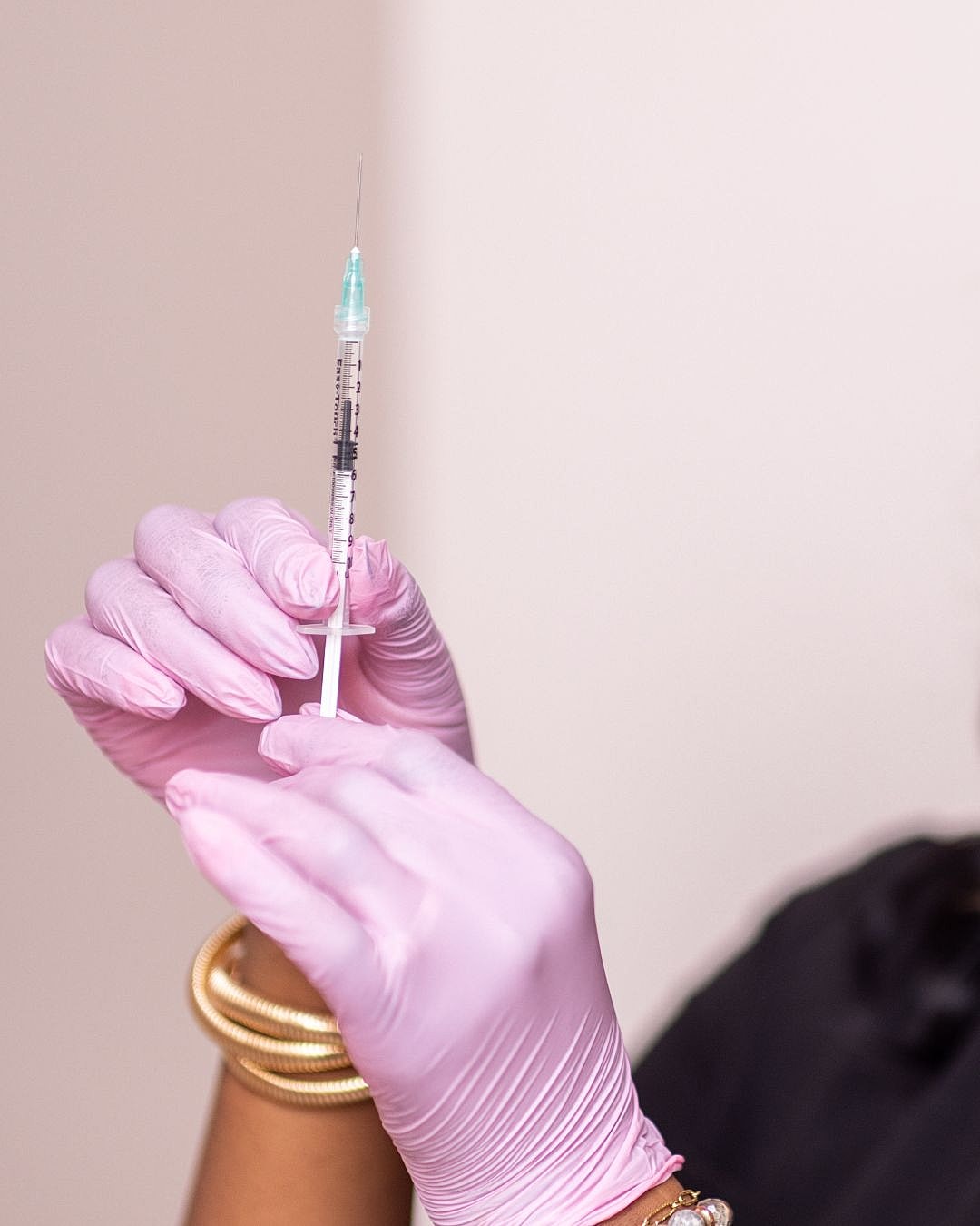 Person in gloves holding a syringe carefully.