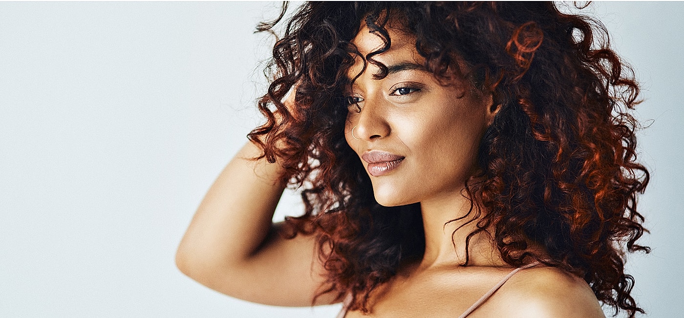 Woman with curly hair against light background.