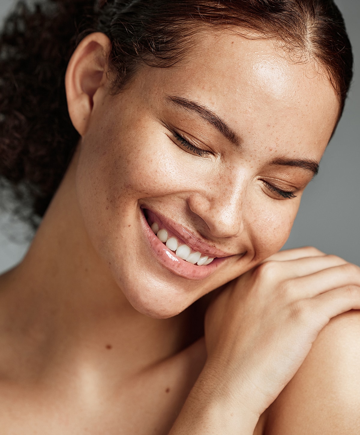 Smiling woman with freckled skin and curly hair.