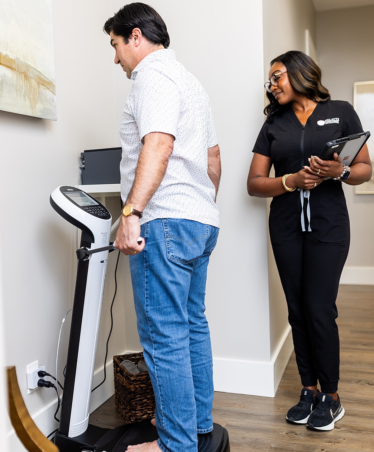 Patient on scale with healthcare professional observing.