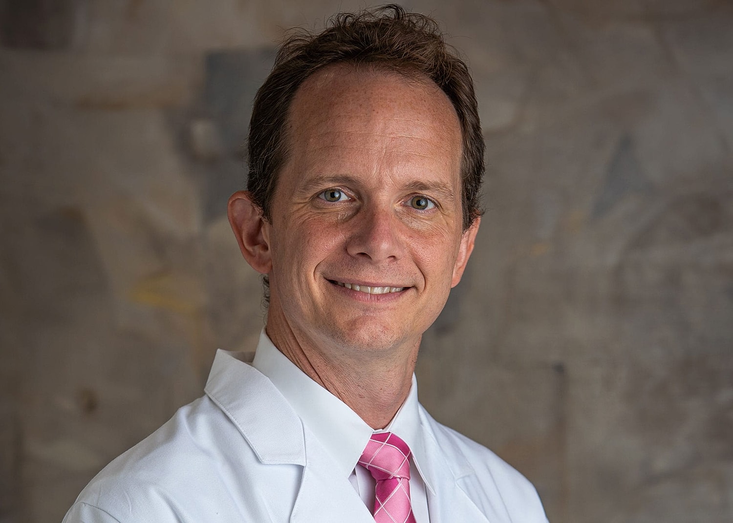 Smiling doctor in a white coat and tie.