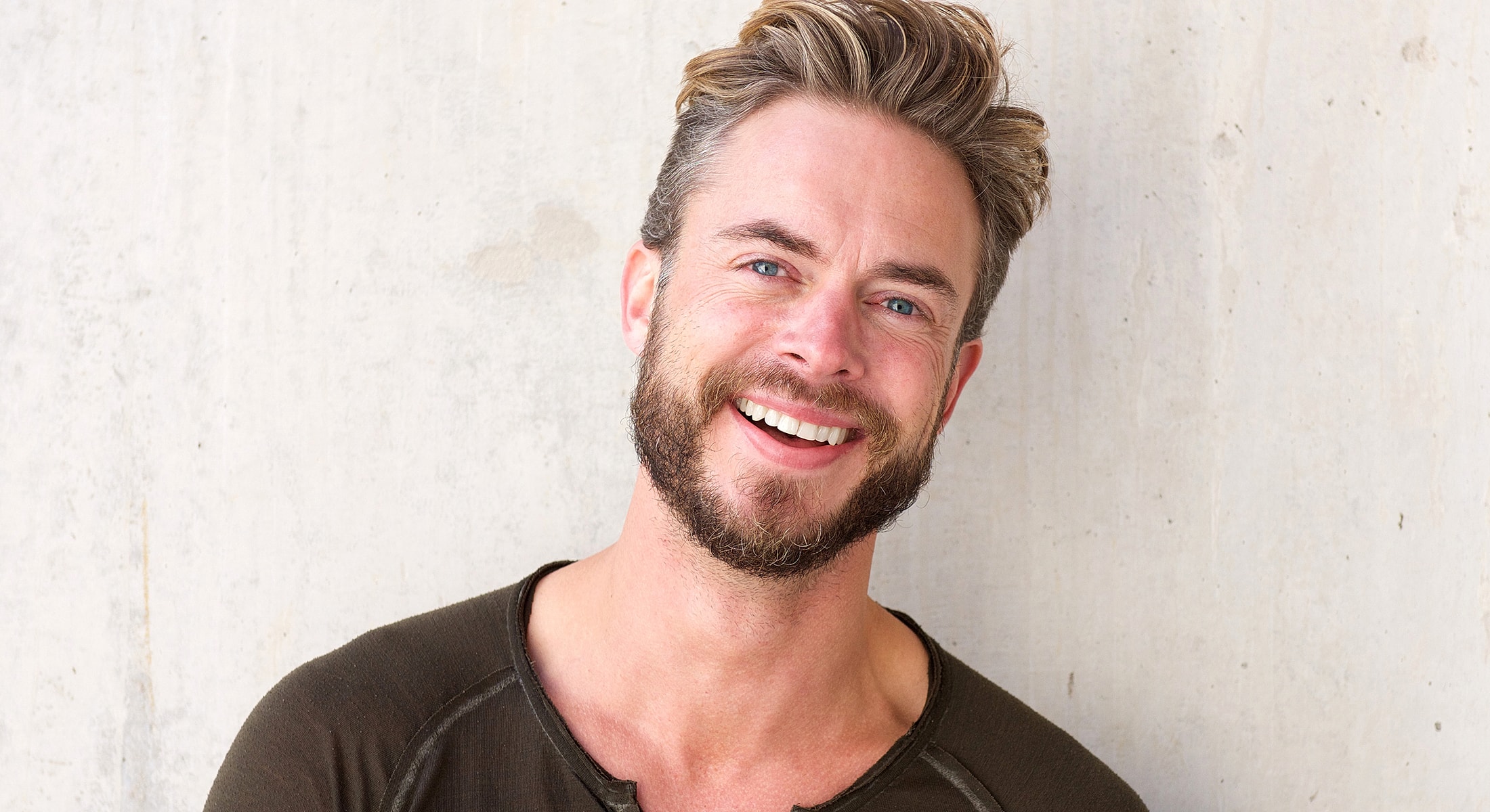 Smiling man with beard against neutral background.