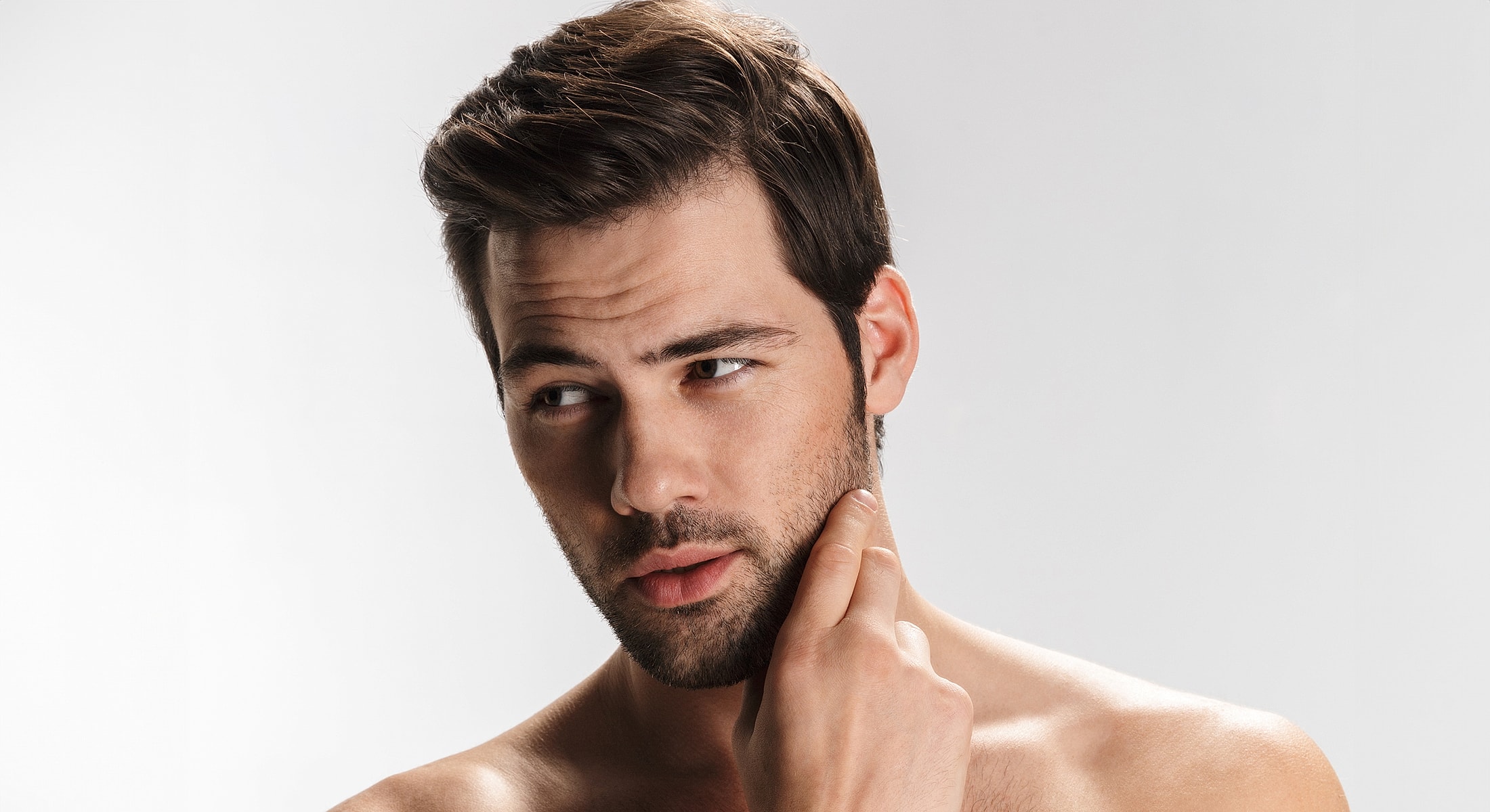 Man with a thoughtful expression touching his face.