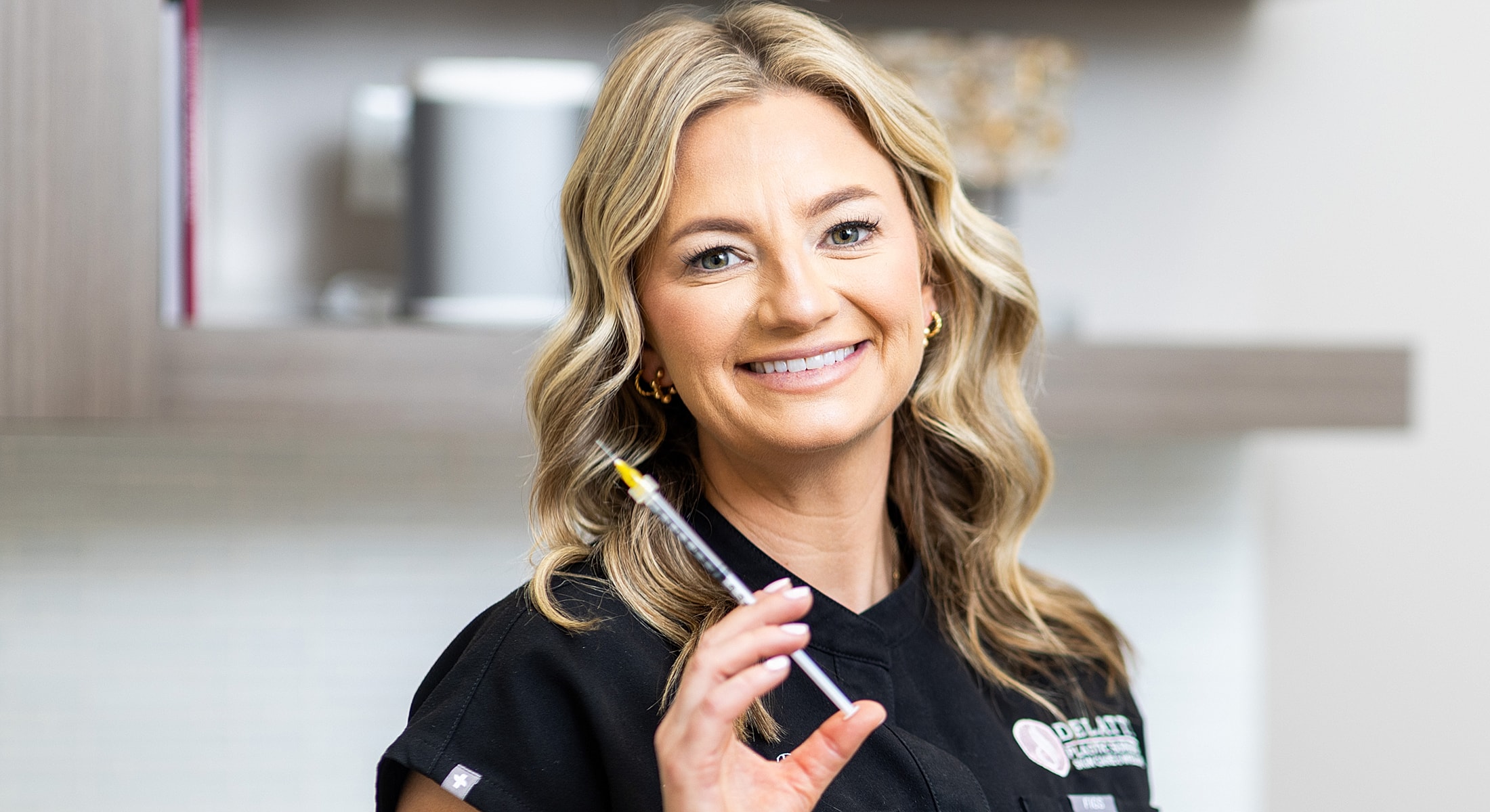 Woman smiling, holding a syringe in clinic.